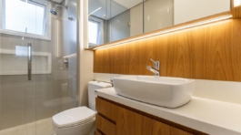 Banheiro da suíte com revestimentos originais em porcelanato fendi, bancada de silestone branco e móvel de marcenaria. Iluminação em LED e nicho embutido no box trazem funcionalidade e conforto ao design.