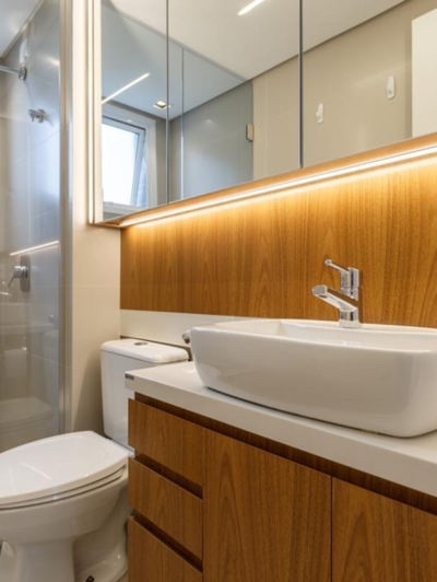 Banheiro da suíte com revestimentos originais em porcelanato fendi, bancada de silestone branco e móvel de marcenaria. Iluminação em LED e nicho embutido no box trazem funcionalidade e conforto ao design.