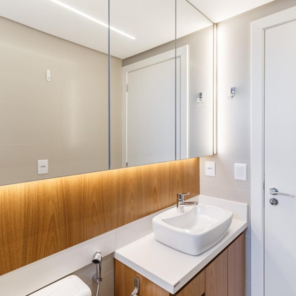 Banheiro da suíte com revestimentos originais em porcelanato fendi, bancada de silestone branco e móvel de marcenaria.