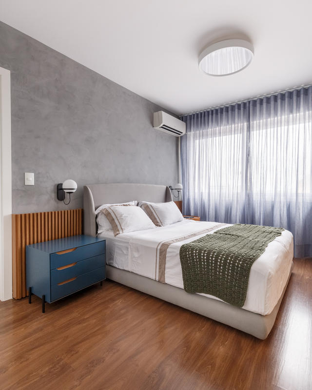 Cama estofada sob medida com criados-mudos assimétricos na suíte planejada